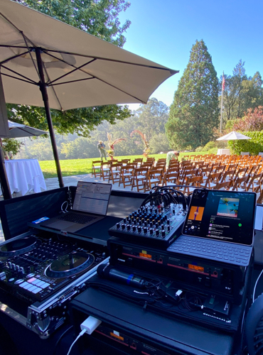 Outdoor wedding setup with chairs and DJ booth